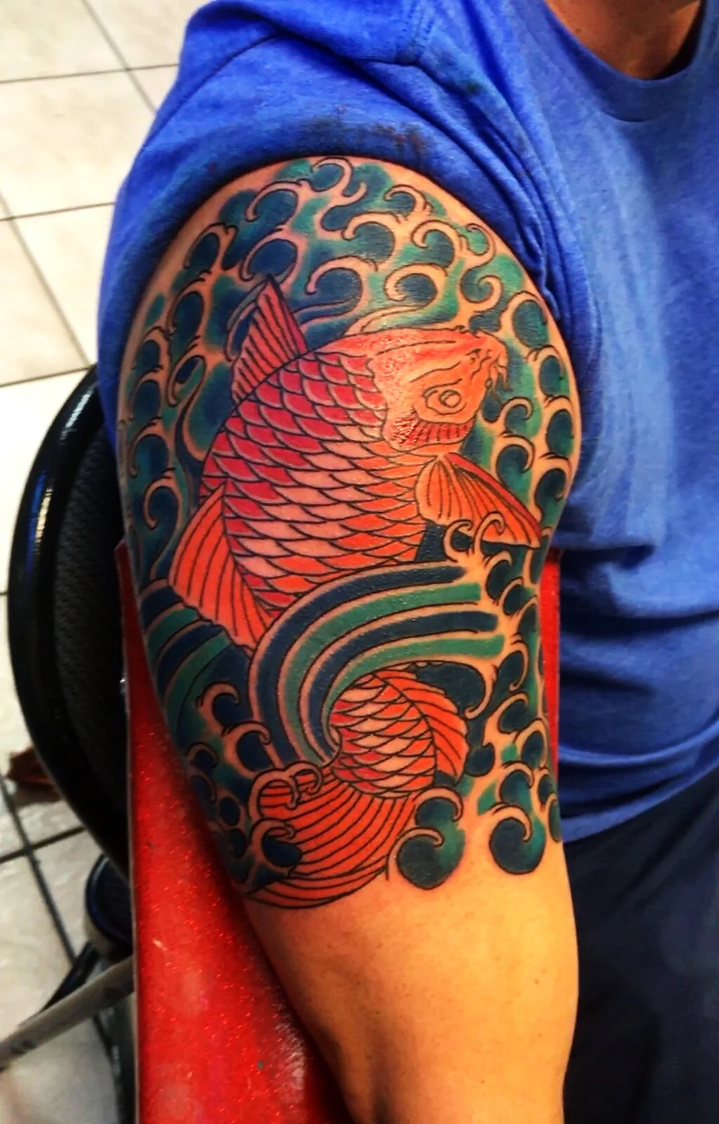 Japanese Wabori red koi fish in teal waves arm tattoo by Tim Goodrich, Waikiki, Hawaii
