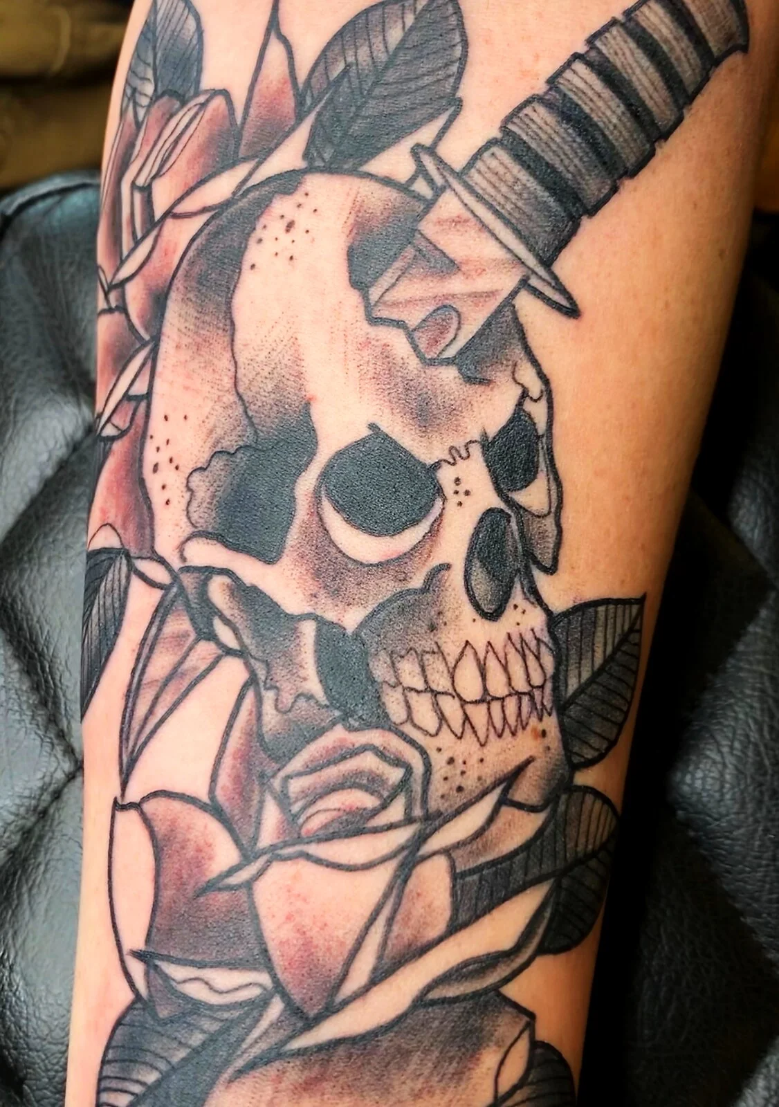 Black and grey skull pierced by dagger with rose bicep tattoo by Tim Goodrich, Waikiki, Hawaii