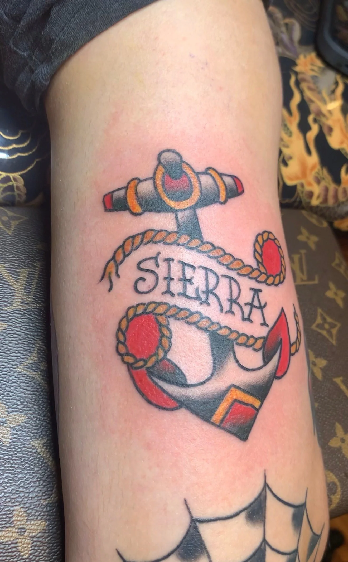 American Traditional color tattoo of a Sailor Jerry style anchor wrapped with a rope banner reading 'SIERRA' on the bicep, by Tim Goodrich at his Waikiki tattoo shop, Hawaii.